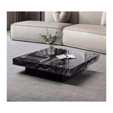 A black marble coffee table with a plant on top, placed in front of a beige sofa on a gray carpet.